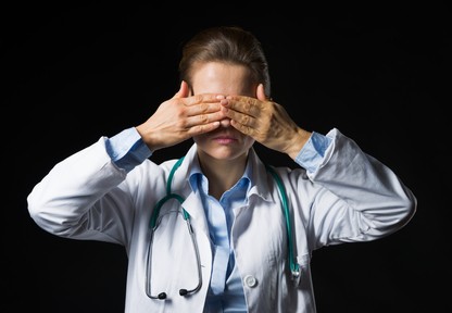 Portrait of doctor woman showing see no evil gesture isolated on black