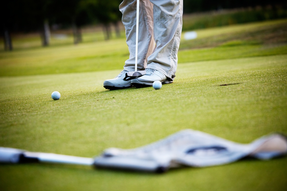 Male golfer putting a golf ball in to hole